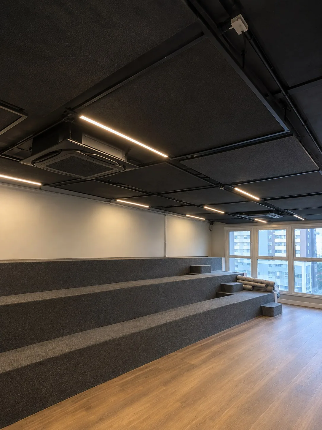 Sala com degraus de assento, forro escuro com iluminação linear e cassete 4 vias