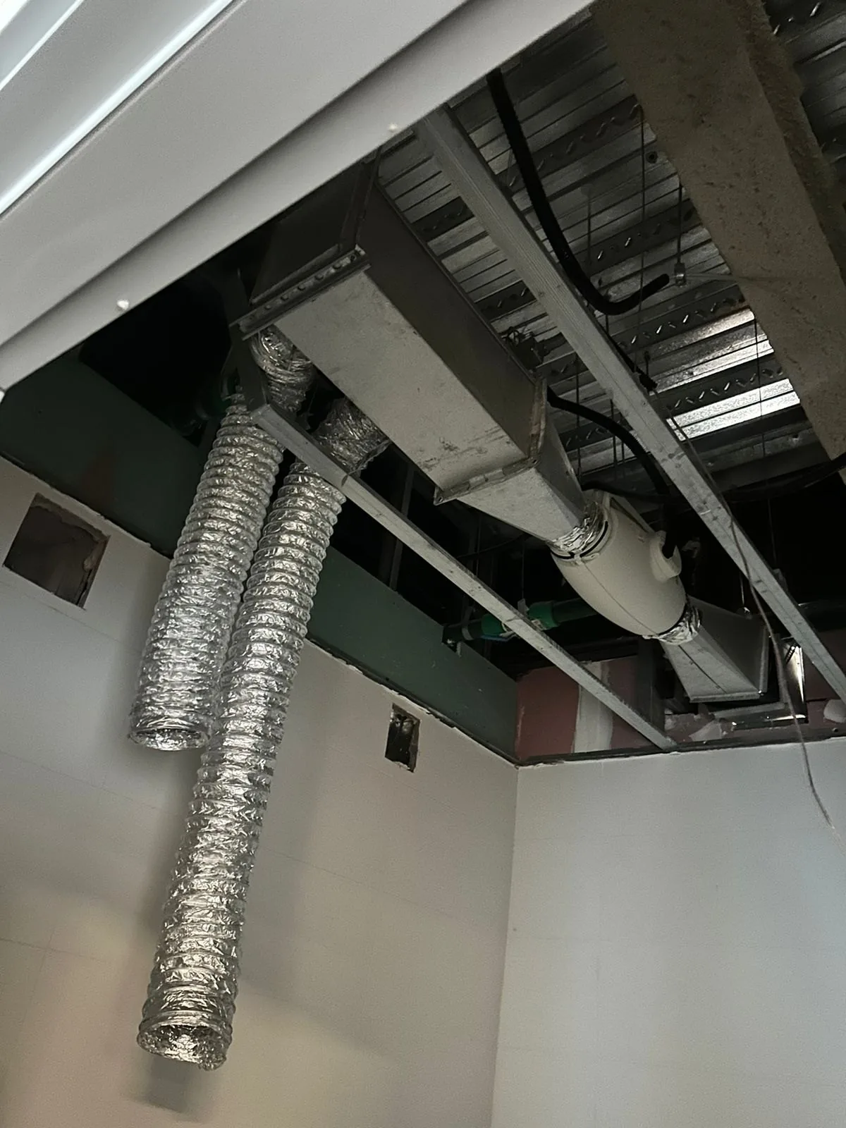 Dutos flexíveis aluminizados e ventilador in-line acima do forro, em ambiente com paredes brancas