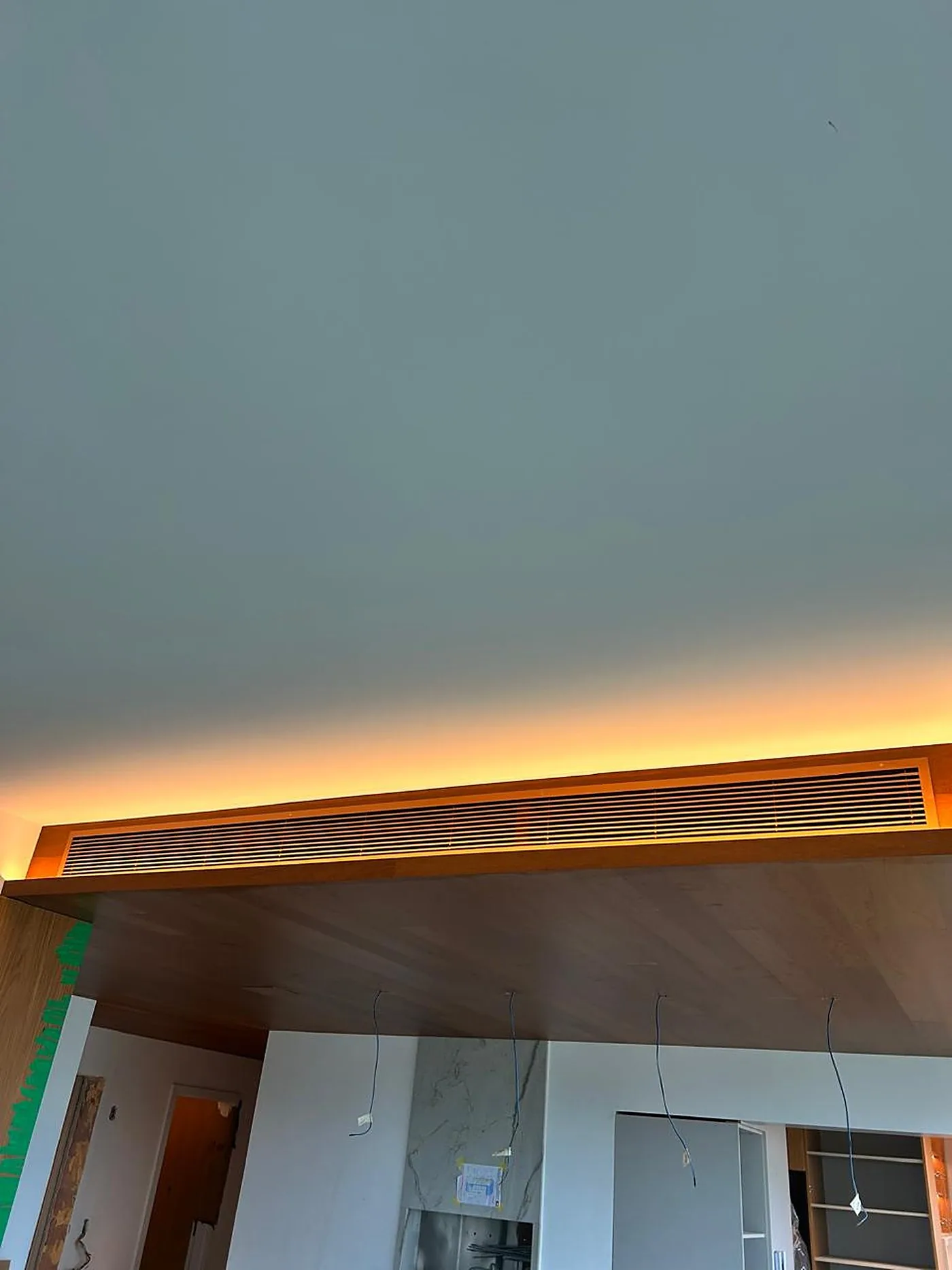 Grelha linear embutida em uma sanca de madeira com iluminação amarela indireta